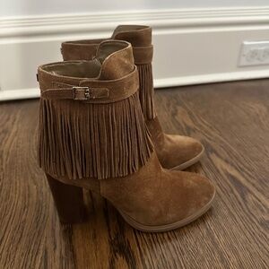This is an Ivanka Trump suede ankle boot with a block heel and fringe detail